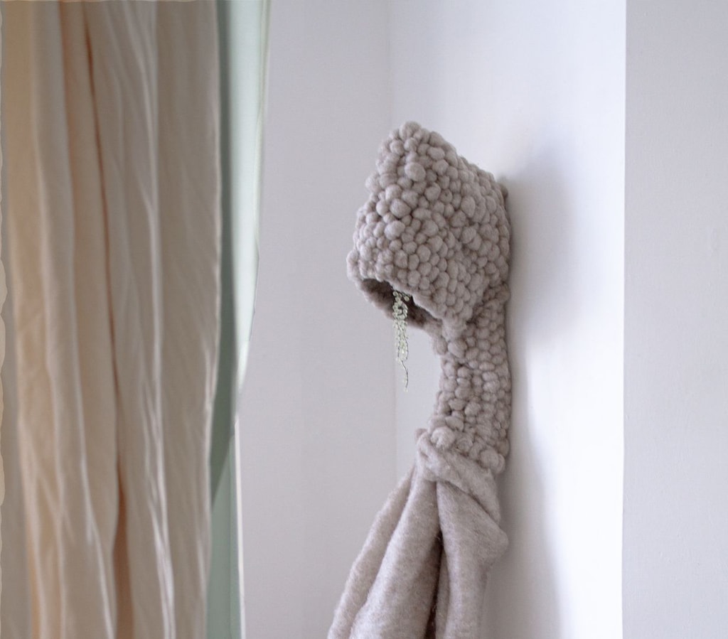 A textile sculpture by Lucie Kordacova appears to be stood upright, with a hooded head from which small beads dangle.