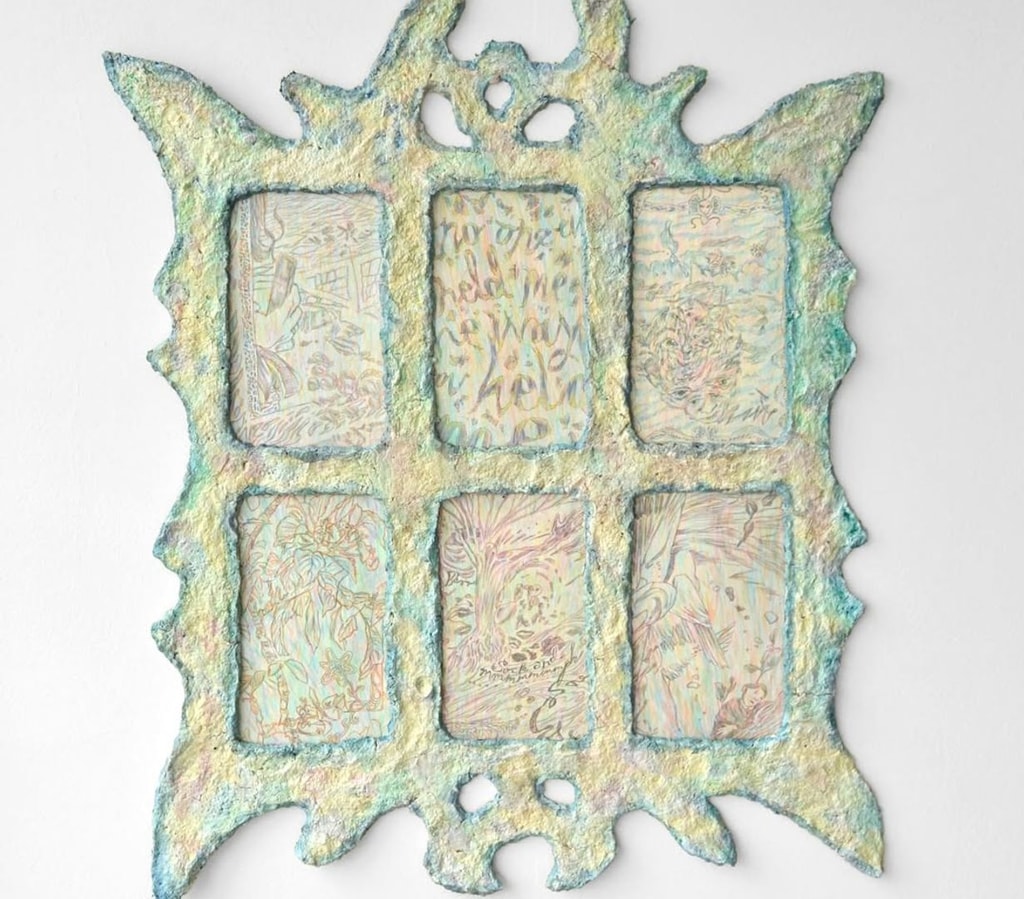 A gothic papier mache window in yellow and blue, with each of its paints featuring a small and heavily detailed Biro drawing.
