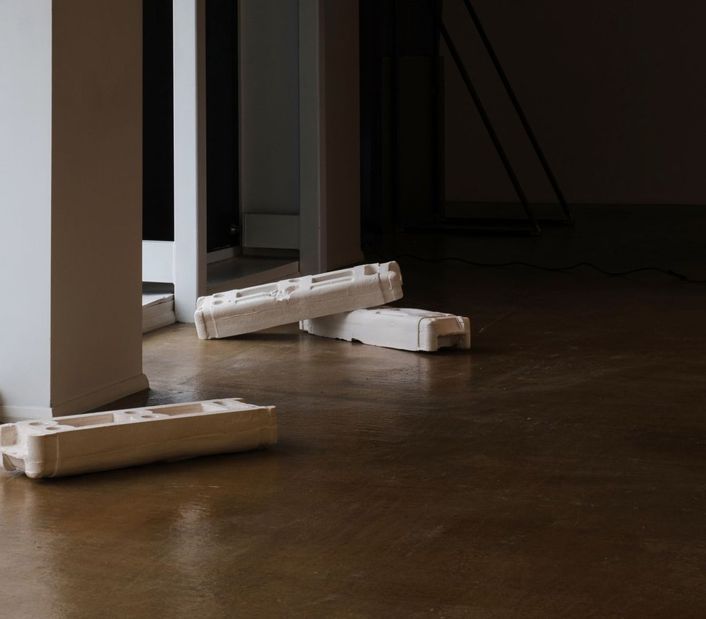 Several pieces of construction materials cast in plaster displayed in a dark room.