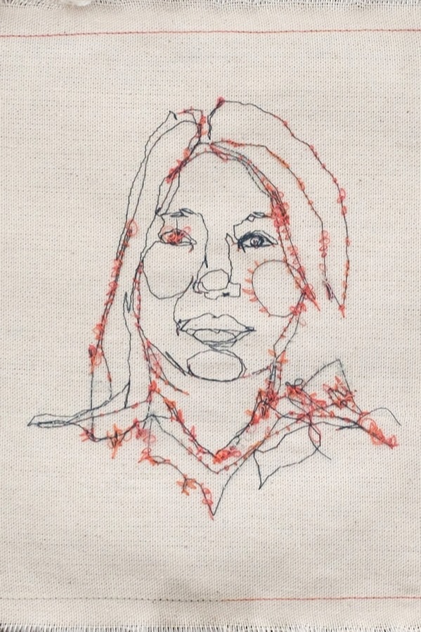Textile work by Liah Edwardes, a portait of a woman in 'continuous line' style, stitched in black and red thread.
