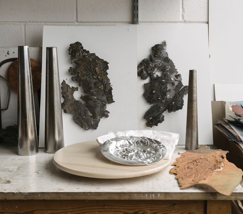 Silver objects displayed on a workbench.