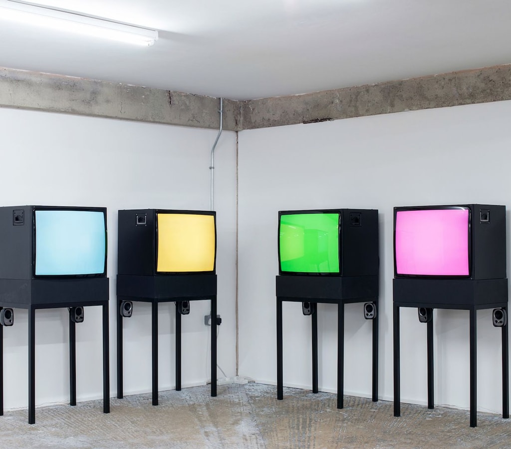 Installation by Vicky Hayward, four CRT monitors arranged in pairs each display a solid colour: blue, yellow, green, and pink.