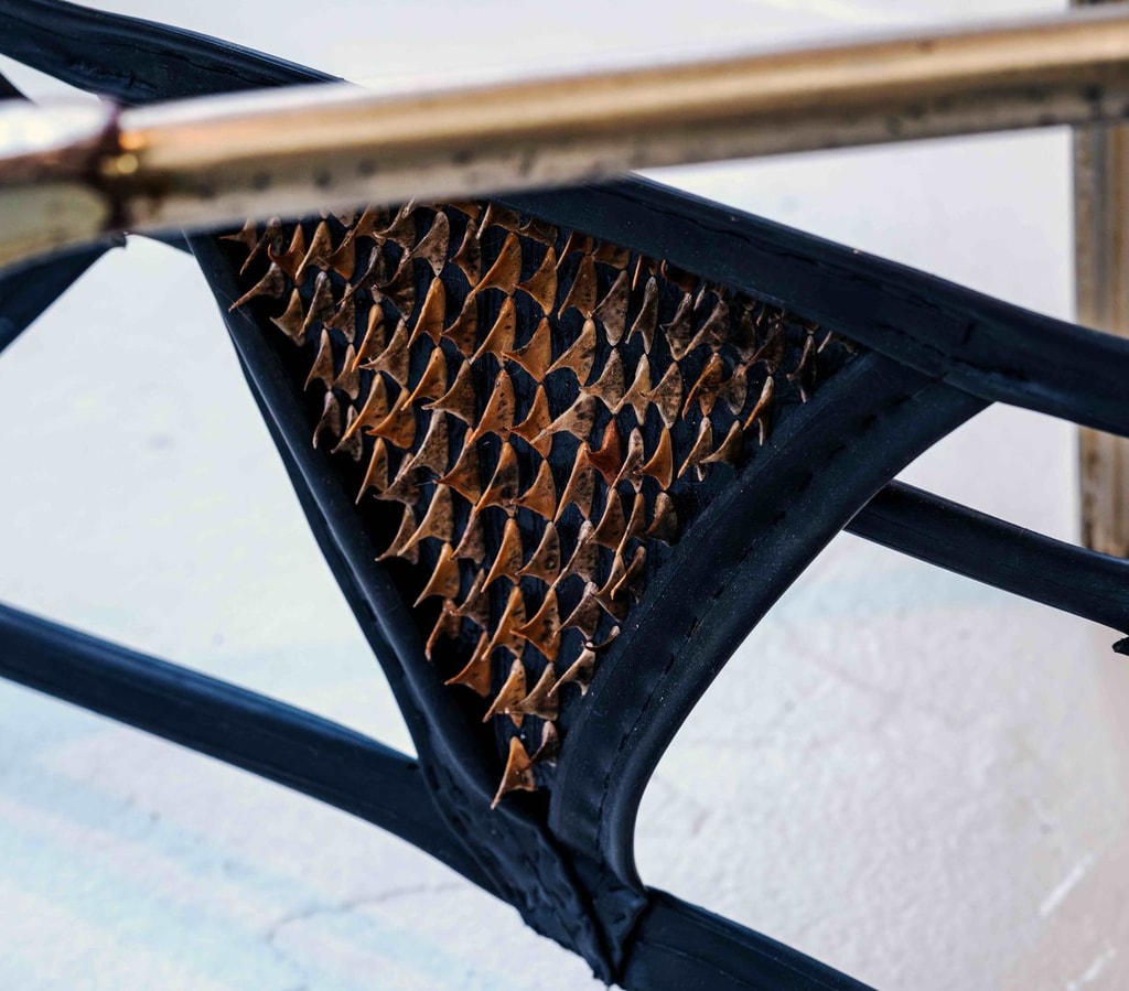 A piece of material strapped to a metal frame, with thorns piercing through.